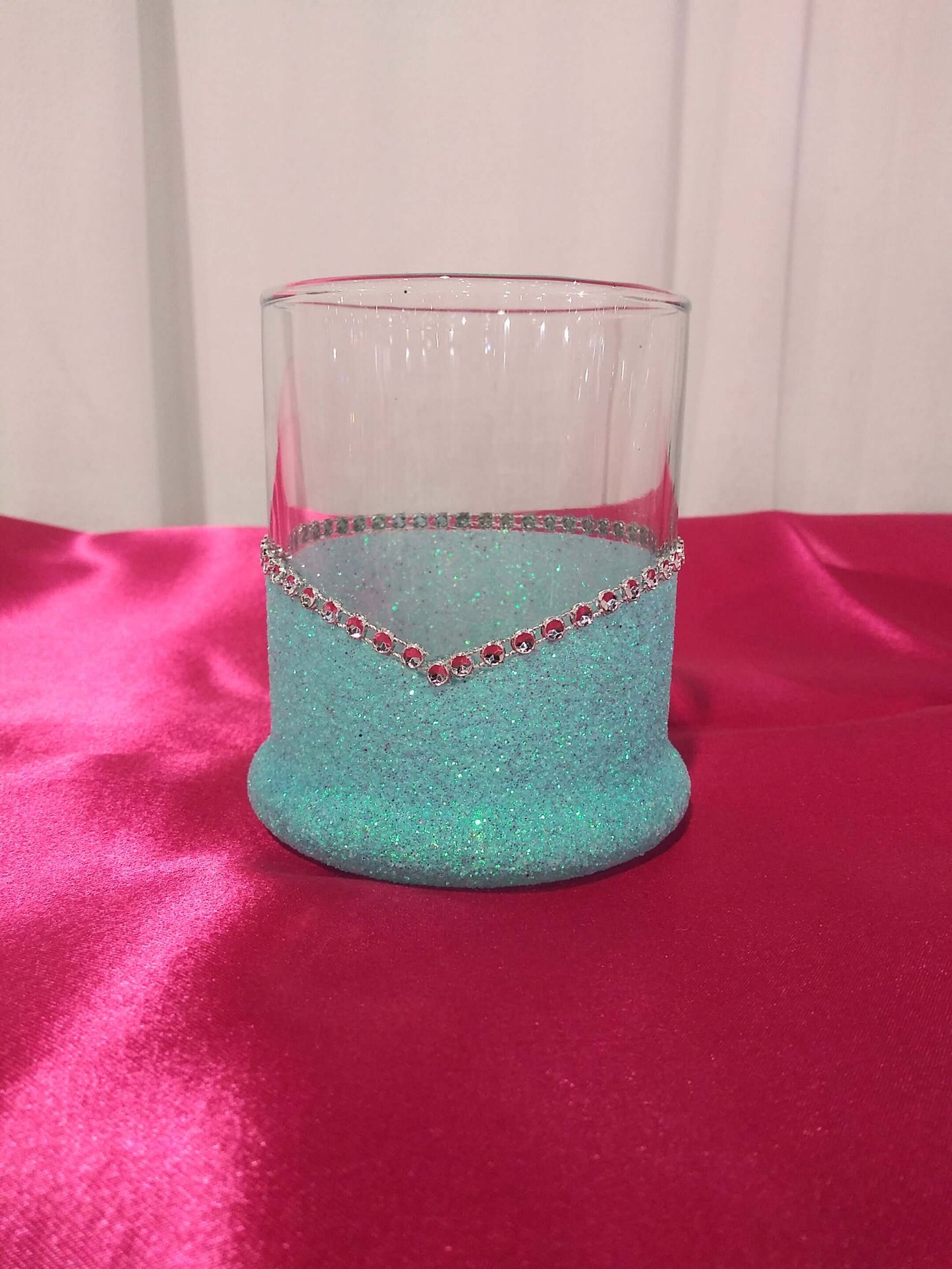 An elegant blinged highball glass with the phrase I Only Have Taste for Whiskey-Halloween Blinged Whiskey-Highball Glasses printed on it and decorated with glitter along the base, displayed on a pink surface.