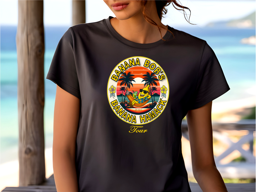 A Women wearing a black t-shirt with a colorful graphic Banana Bob's Banana Hamack Tourdesign in front of a beach.