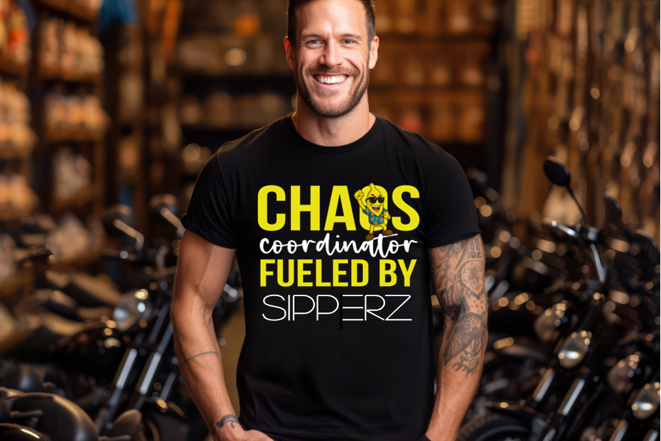 Man wearing a black t-shirt with yellow and white text Banana Bob's Chaos Coordinator Fueled By Sipperz in a motorcycle shop.