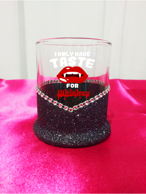 Glass tumbler with black glitter base and red text I Only Have Taste for Whiskey-Halloween Blinged Whiskey-Highball Glass on a pink surface