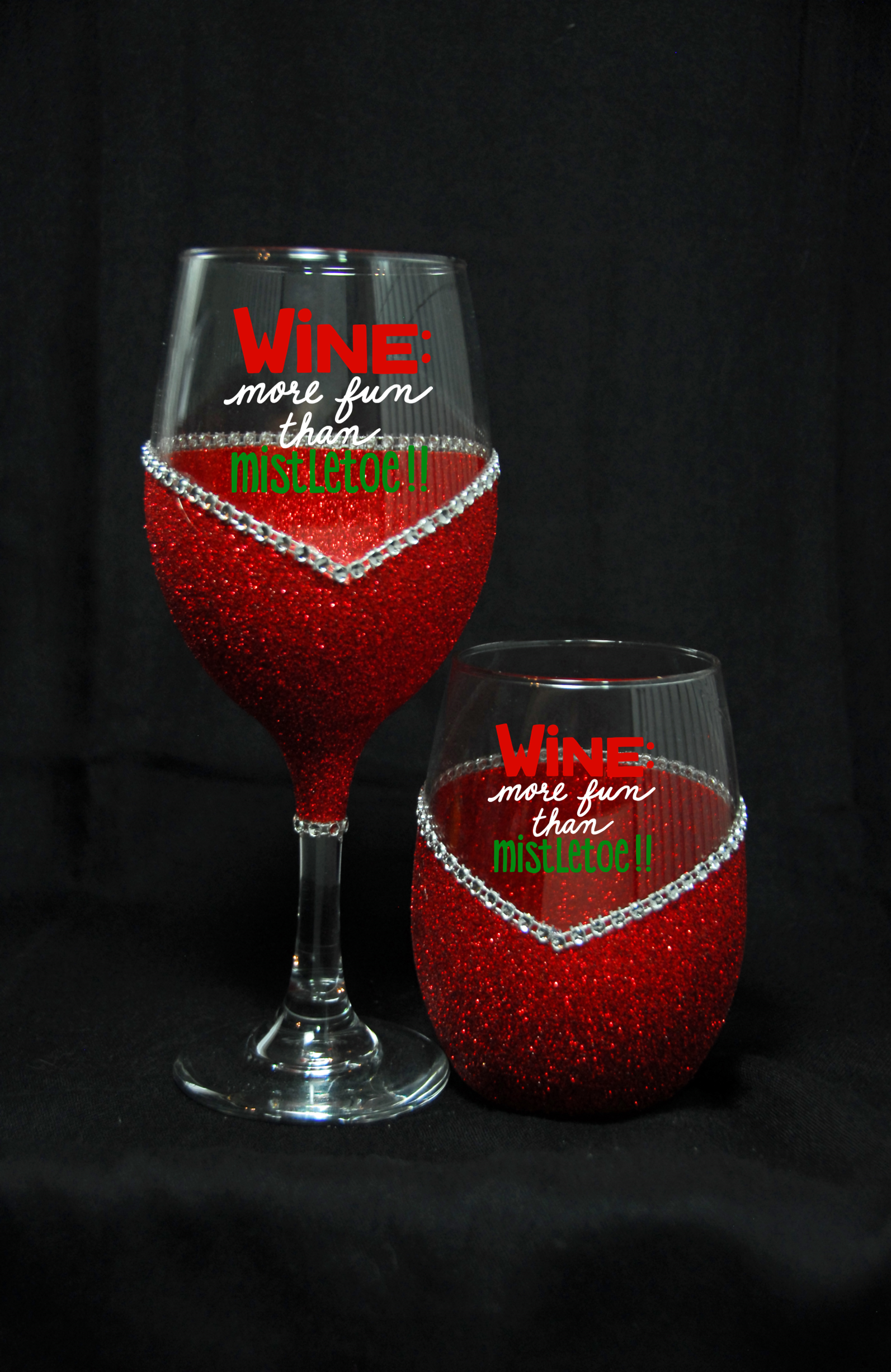 Two red wine glasses with decorative text on a black background
