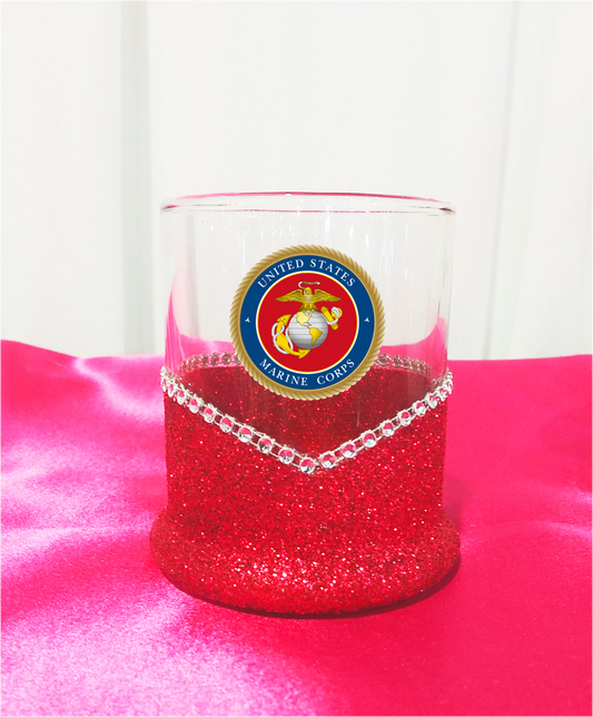 Whiskey highball Glass tumbler with red glittery base and US Marine Corps emblem on a pink surface